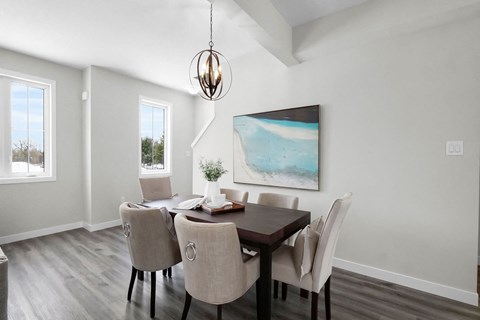 A dining room with a table set for two and a painting on the wall.