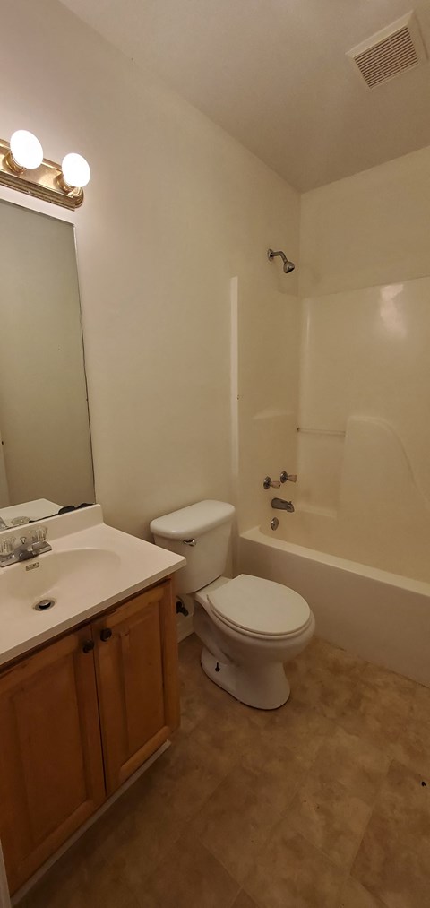 A white toilet sits in a bathroom next to a sink.
