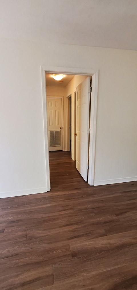 A hallway with a wooden floor and white walls.