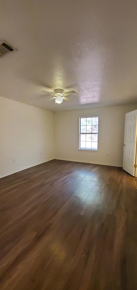 A room with wooden floors and a ceiling fan.