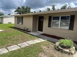 A beige house with a black door and a small front yard.