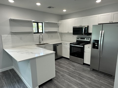 A kitchen with white cabinets and a white counter top.