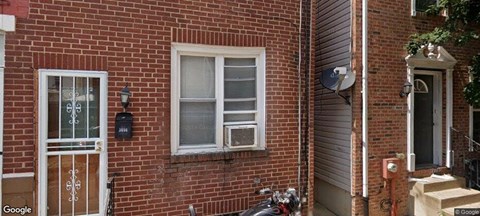 A red brick house with a white door and a window.