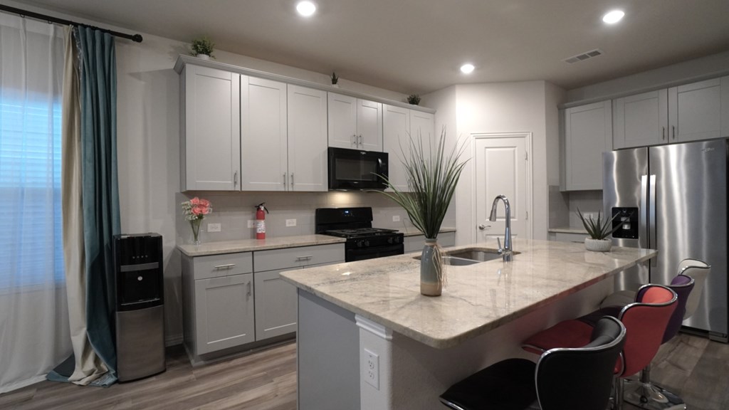 A kitchen with white cabinets and a marble countertop.