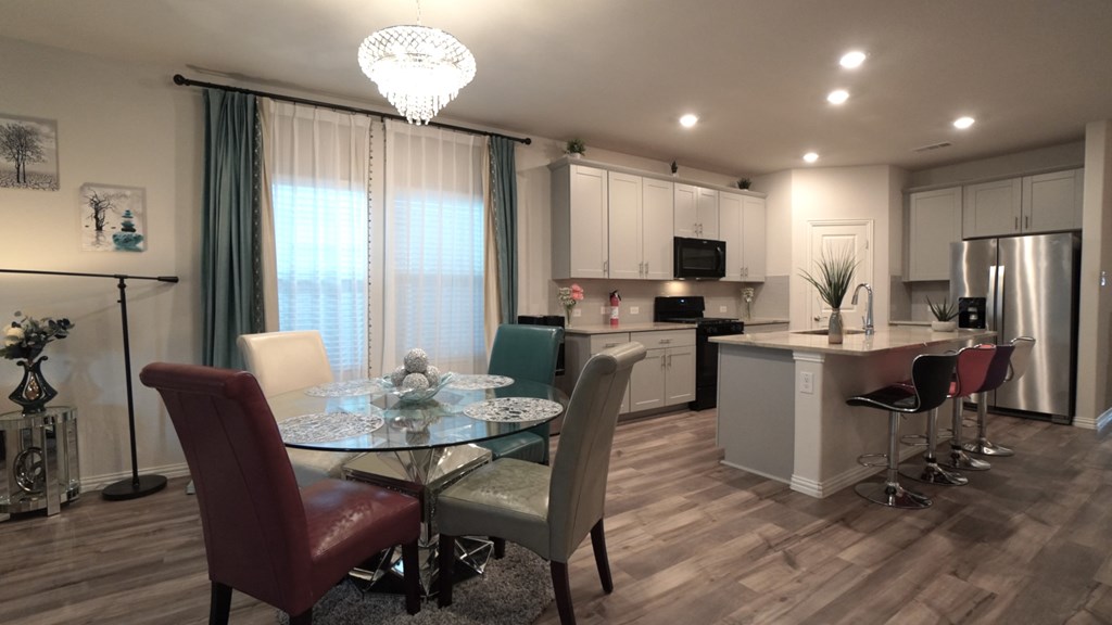 A modern kitchen with a glass dining table and chairs.