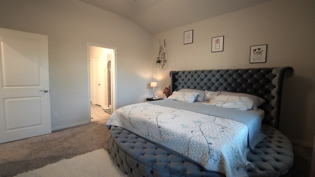 A bedroom with a large bed and a rug on the floor.