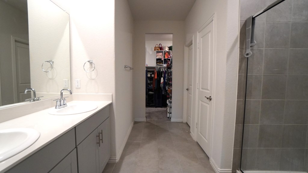 A bathroom with a sink, mirror, and a walk in shower.