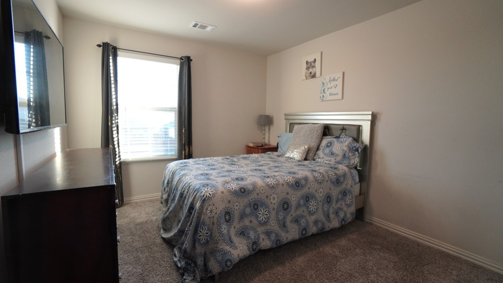 A bedroom with a bed, nightstand, and window.