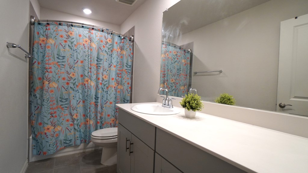 A bathroom with a toilet, sink, and shower curtain.