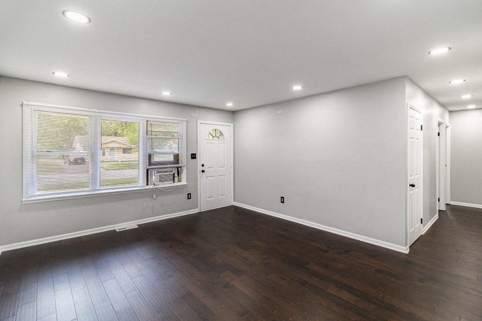 A spacious room with wooden floors and white walls.