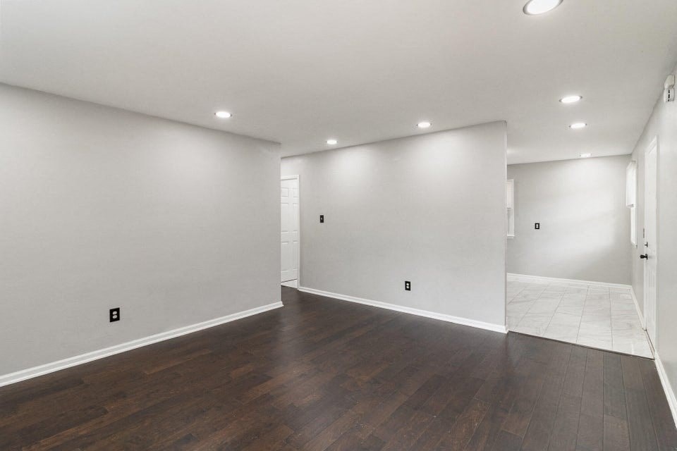 A large empty room with wooden floors and white walls.