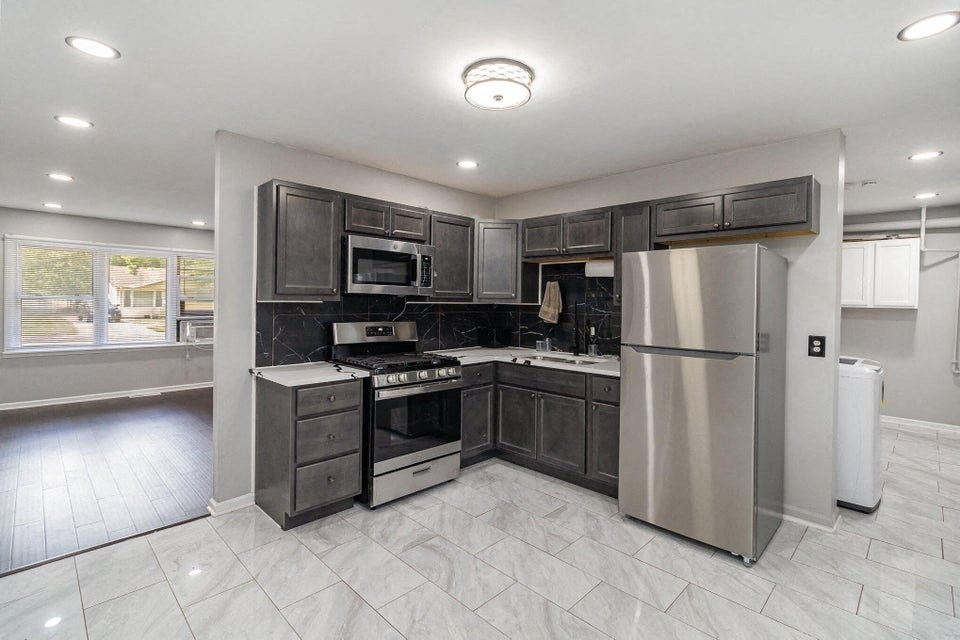 A modern kitchen with stainless steel appliances and a marble floor.