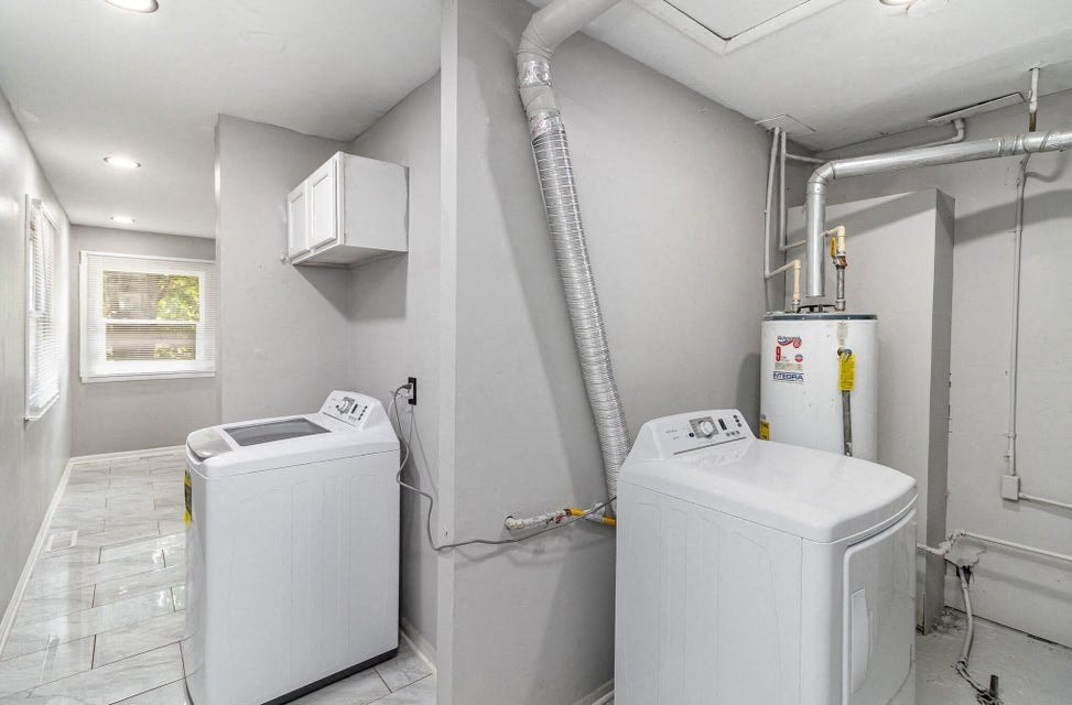 A room with two white washing machines and a grey wall.