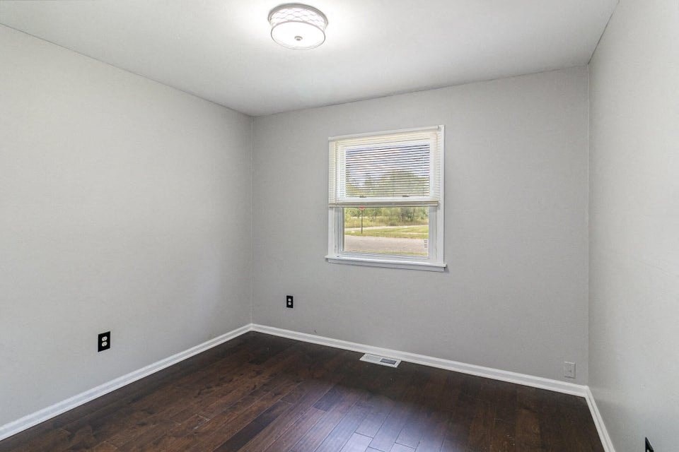 A room with a window and a smoke detector on the ceiling.