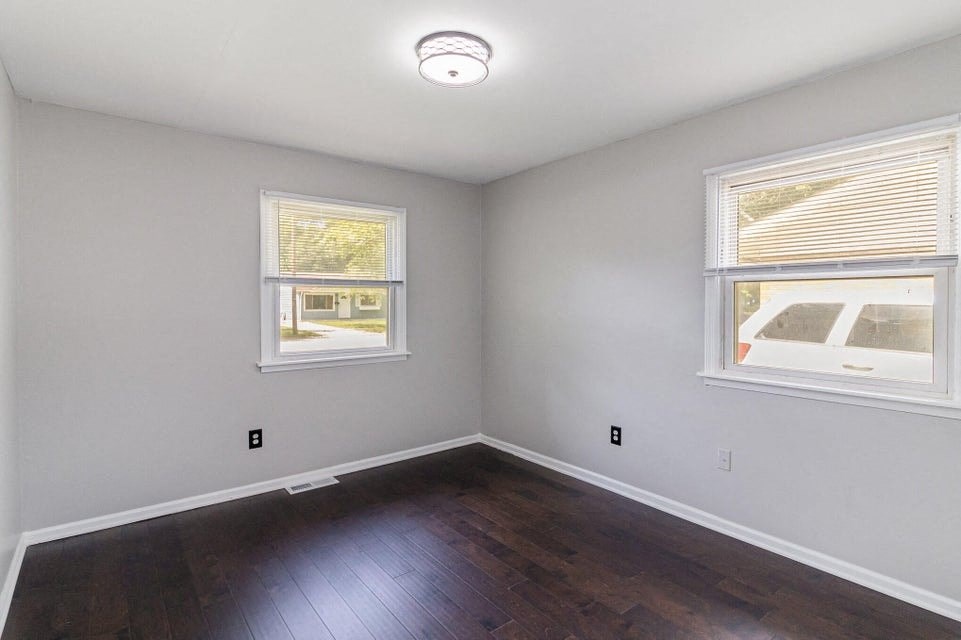 A room with a window and a smoke detector on the ceiling.