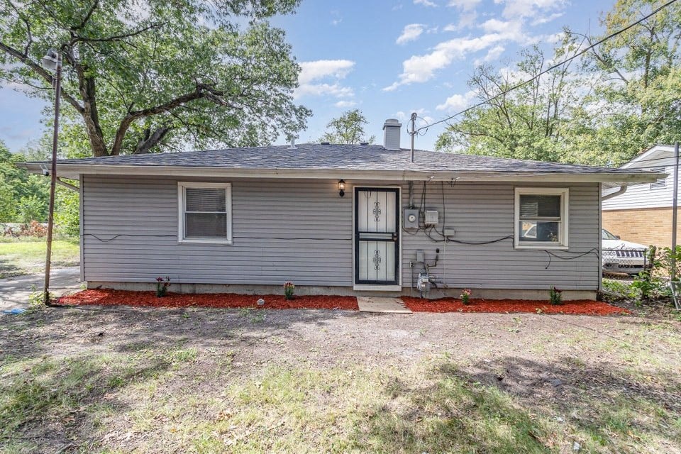 A small grey house with a red border around the foundation.
