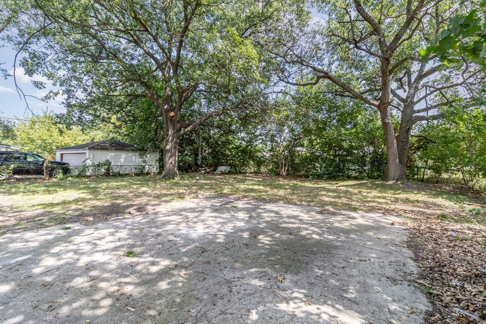 A backyard with a dirt ground and trees.