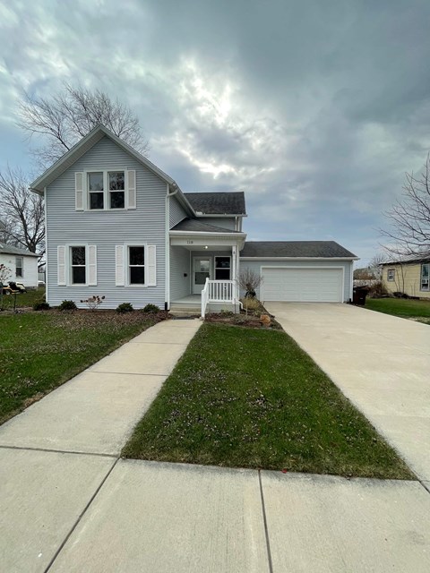 A grey house with a white garage door and a small front yard.