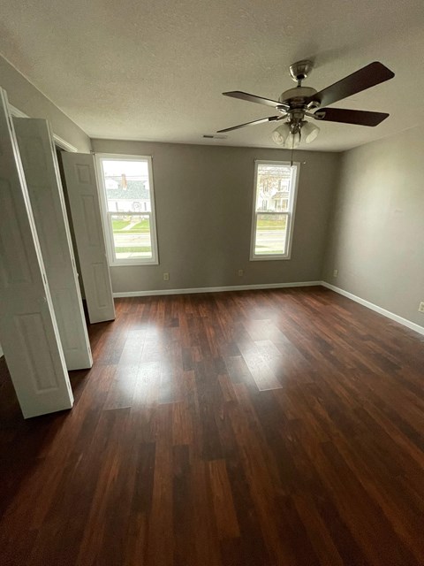 A room with a ceiling fan and wood flooring.