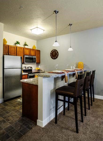 a kitchen with a bar and chairs and a refrigerator