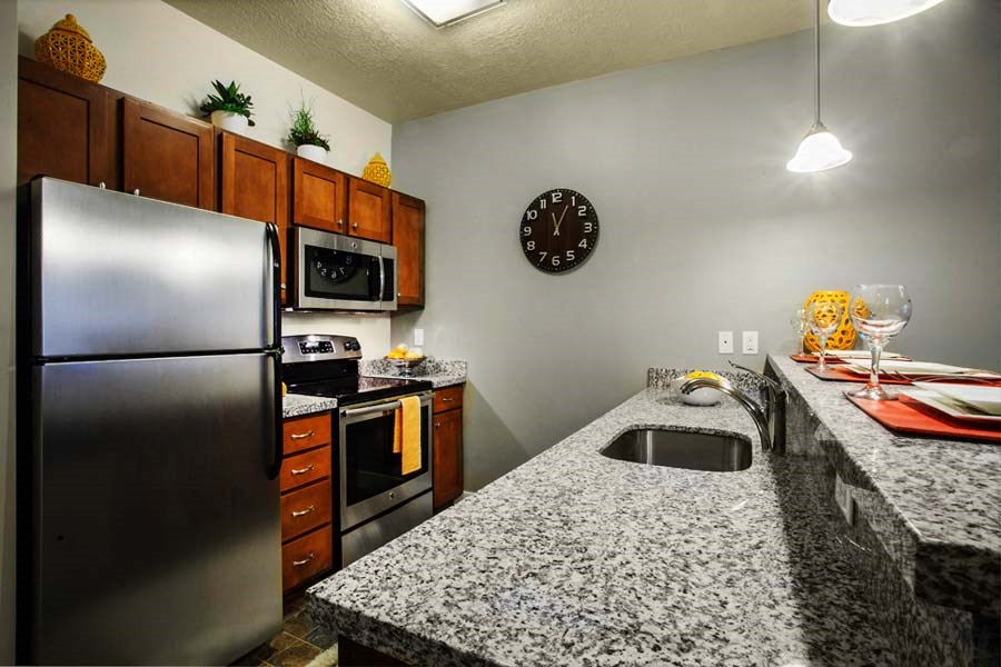 a kitchen with granite counter tops and a stainless steel refrigerator