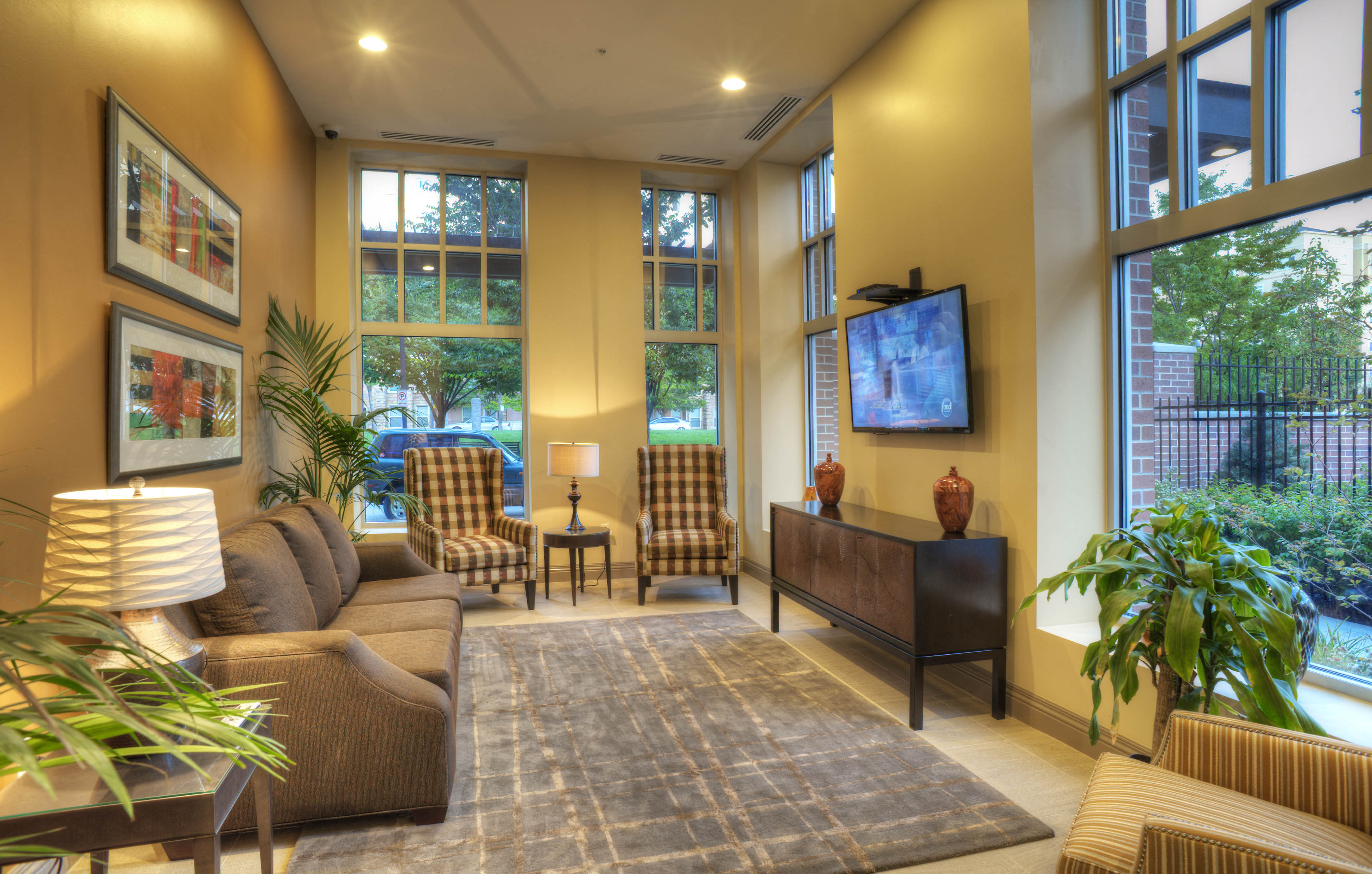a living room with a couch and chairs and large windows