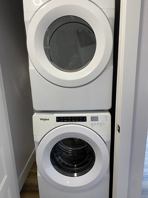 A white Whirlpool washing machine and dryer in a small laundry room.
