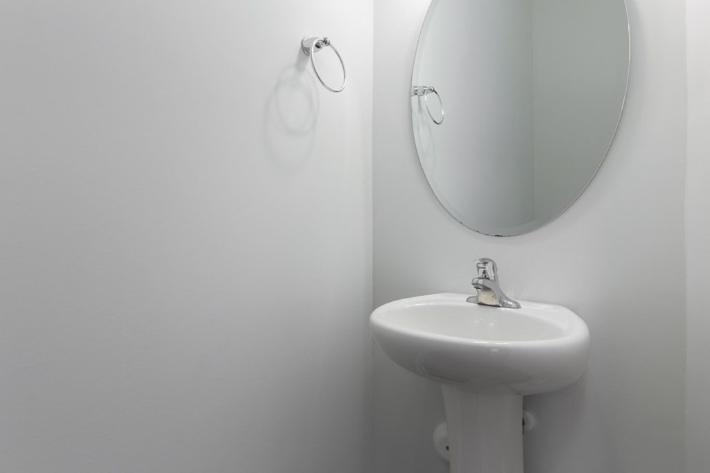 A white sink with a round mirror above it.