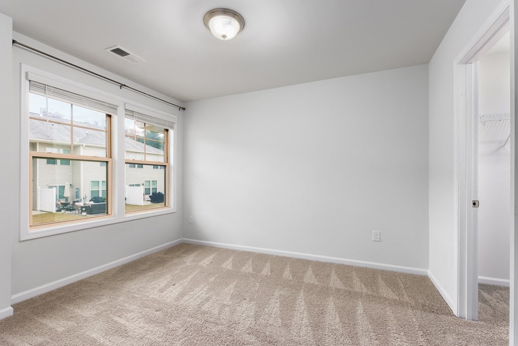 A room with a carpeted floor and a window.