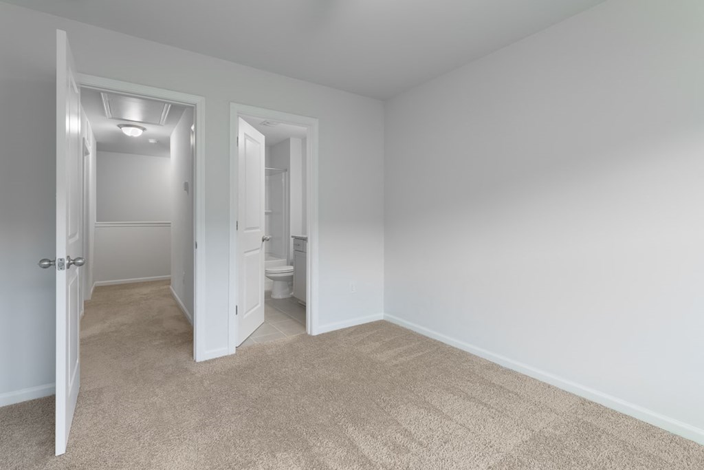 A room with carpeted floors and two open doors.