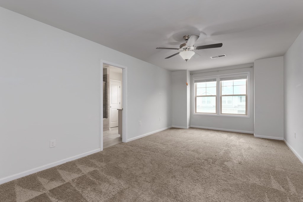 A room with a ceiling fan and carpeted floor.
