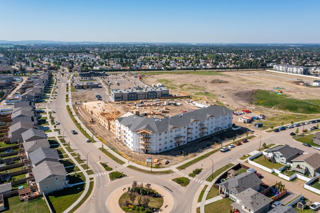 A large white building is under construction in the middle of a suburban area.