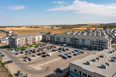 A parking lot with cars and apartment buildings in the background.