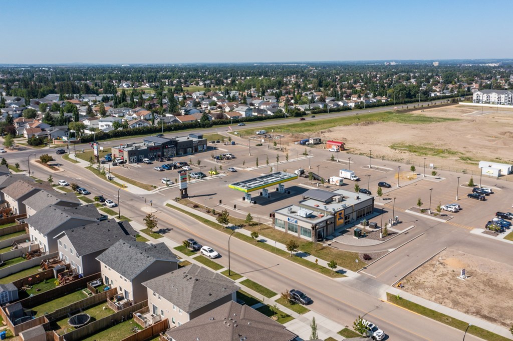 A view of a residential area with houses, a parking lot, and a road.