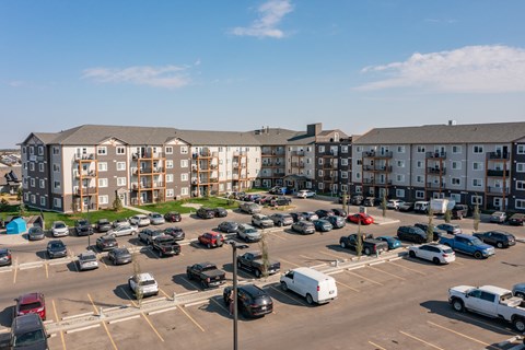 A parking lot with cars and apartment buildings in the background.