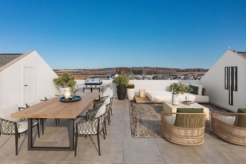 A modern outdoor dining area with a wooden table and chairs.