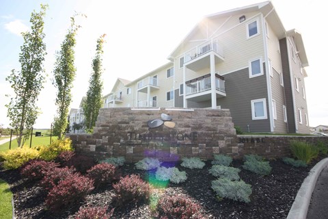 A modern apartment building with a landscaped garden in front.