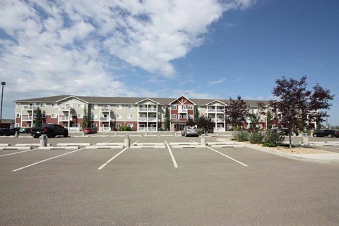 A parking lot in front of a building with cars parked.