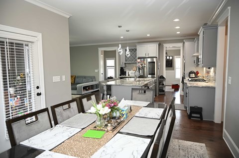 A kitchen with a table set for four with a green napkin on it.