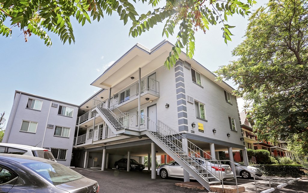 a white apartment building with stairs and cars parked in front of it