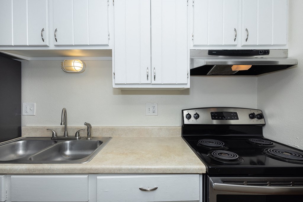 a kitchen with white cabinets and a stove and sink