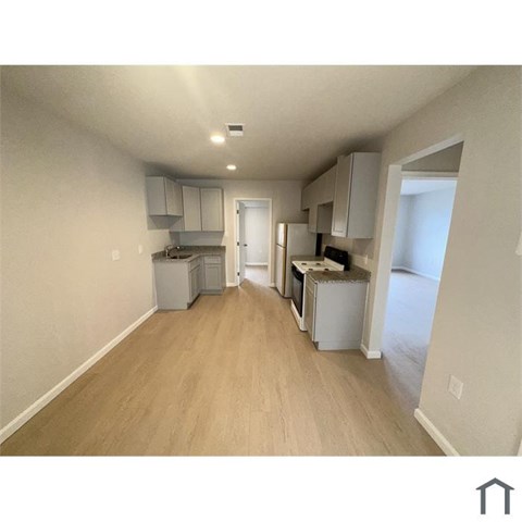 A kitchen area with white appliances and wooden floors.
