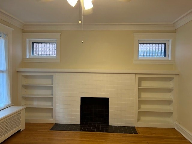 A white fireplace with a black grate in a room with wooden floors and white walls.