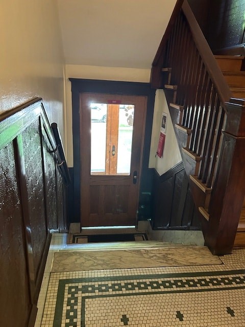 A hallway with a wooden staircase and a tiled floor.