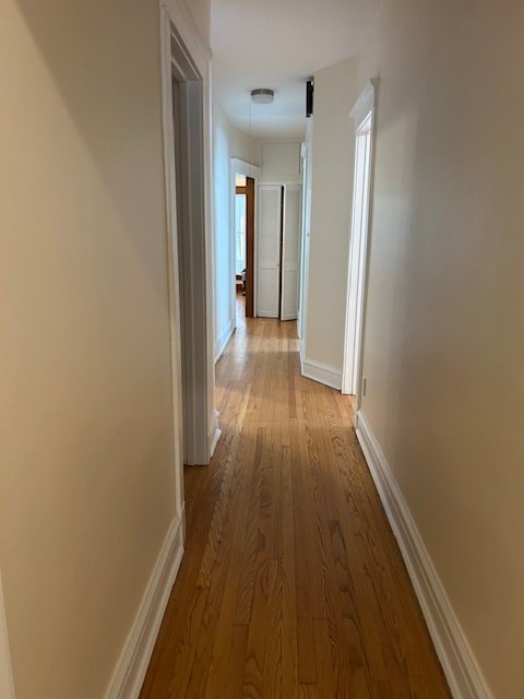 A long hallway with wood floors and white walls.