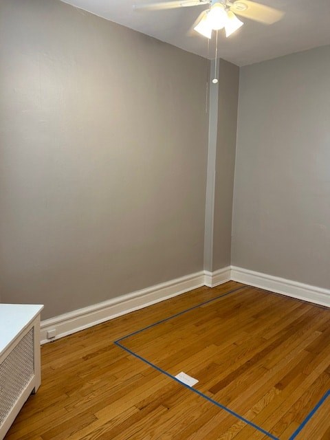 A room with a ceiling fan and a wooden floor.