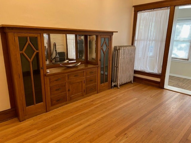 A room with wooden floors and furniture including a wooden cabinet with glass doors and drawers.