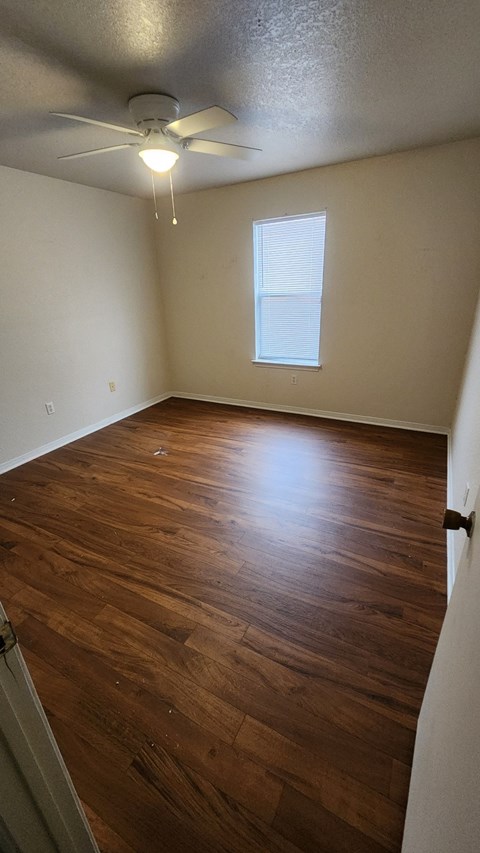 A room with a ceiling fan and wooden flooring.