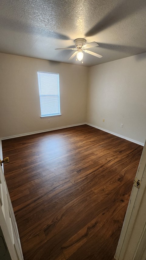 A room with a ceiling fan and wooden flooring.