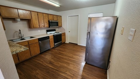 A kitchen with wooden cabinets and a black refrigerator.